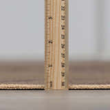 Close-up of the Hamid Washable Jutely Rug showing the pile height with a ruler, revealing its low profile. Pile