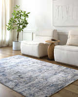 Living room scene with a blue and gray Hyman Area Rug, two white armchairs, and wood floors. Roomscene-Rectangle