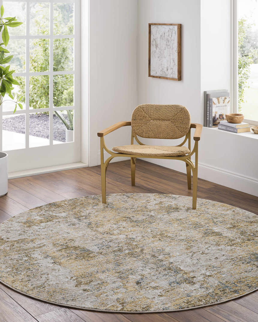 Light-filled room with round Aleka Rich Textured Rug in bone, gold, and gray under a woven chair on wood floors. Roomscene-Round