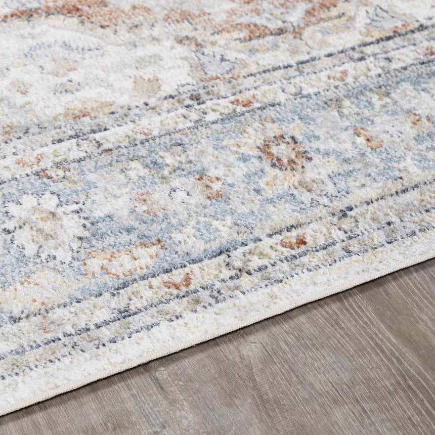 Close-up of the Emke Flat Pile Washable Rug. Features a traditional pattern in bone, beige, blue, and brown tones. Pile