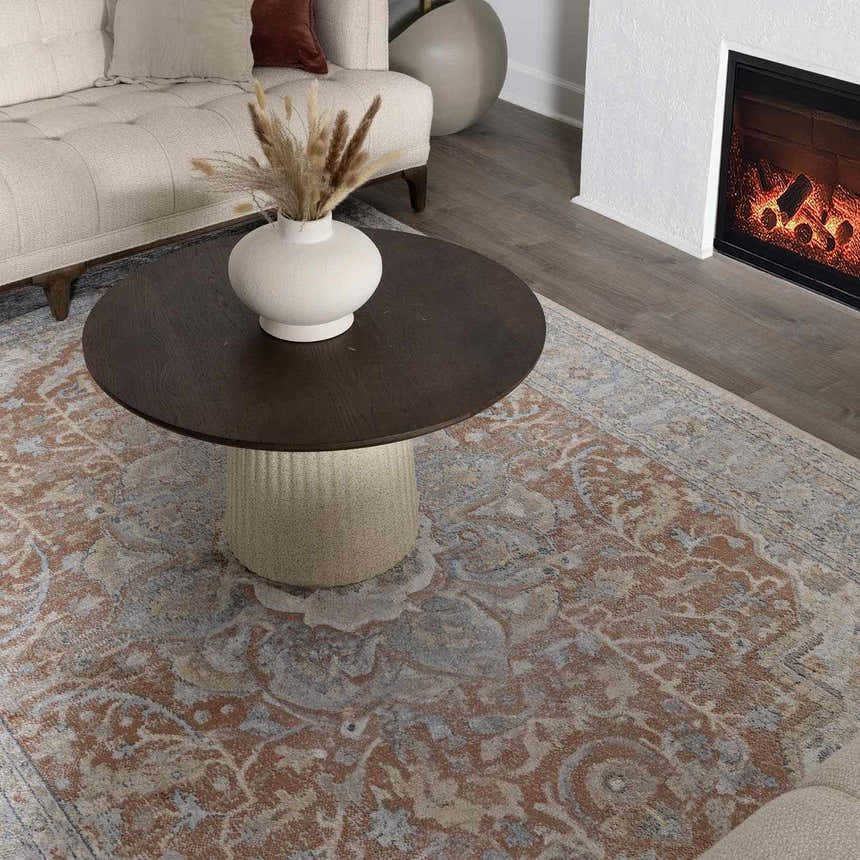 Living room scene with a bone sofa, fireplace, and rust-colored Emke Flat Pile Washable Rug with a traditional floral pattern. Roomscene-Rectangle