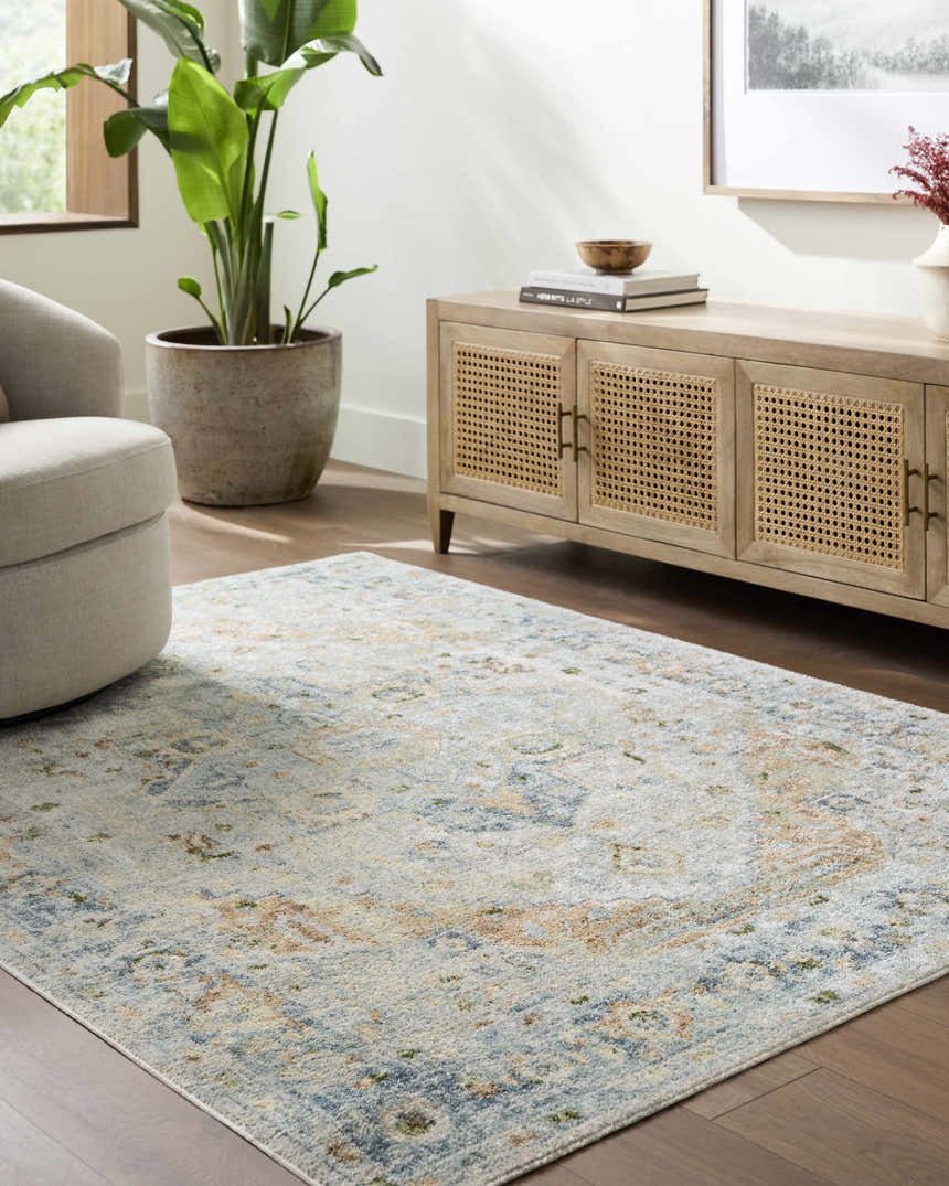 Living room scene with Ezri Washable Area Rug in beige, light blue, and orange. Farmhouse style with wood cabinet and neutral armchair. Roomscene-Rectangle