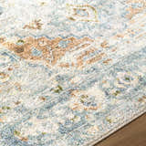 Close-up of the Ezri Washable Area Rug featuring a traditional pattern in beige, light blue, and orange hues. Texture