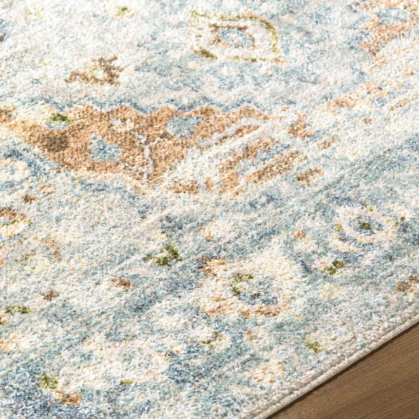 Close-up of the Ezri Washable Area Rug featuring a traditional pattern in beige, light blue, and orange hues. Texture