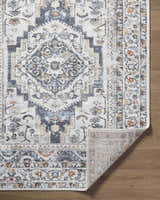 Close-up of the Paula Off White Area Rug showing its traditional charcoal, brown, and mustard floral pattern. Fold