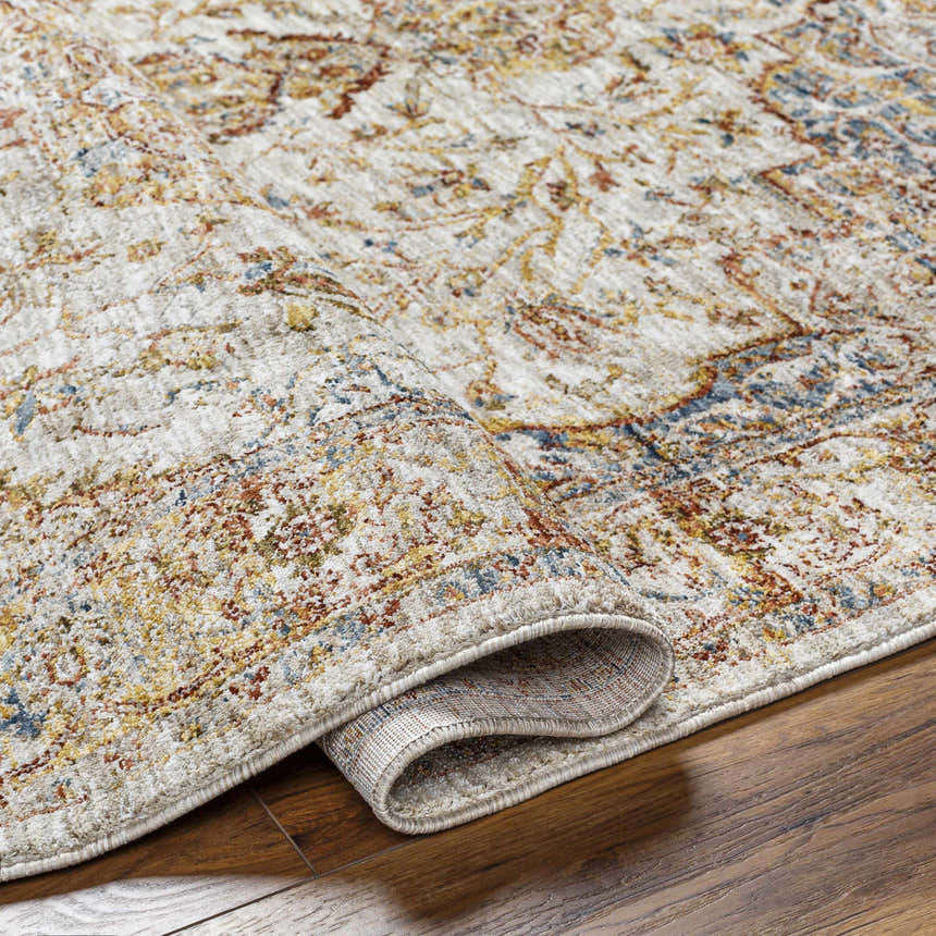Close-up of the Aman Beige Area Rug showing its traditional pattern, brick red, mustard, and blue colors, and soft texture. Fold