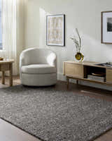 Living room scene with gray Sevan Black Wool Area Rug, cream chair, and wood media console. Roomscene-Rectangle
