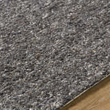 Close-up of the hand-tufted Sevan Black Wool Area Rug showing its texture and blend of jet black, gray, and taupe tones. Texture