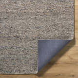 Close-up of the hand-tufted Sevan Taupe Wool Area Rug showing its neutral colors and textured wool pile on a wood floor. Fold