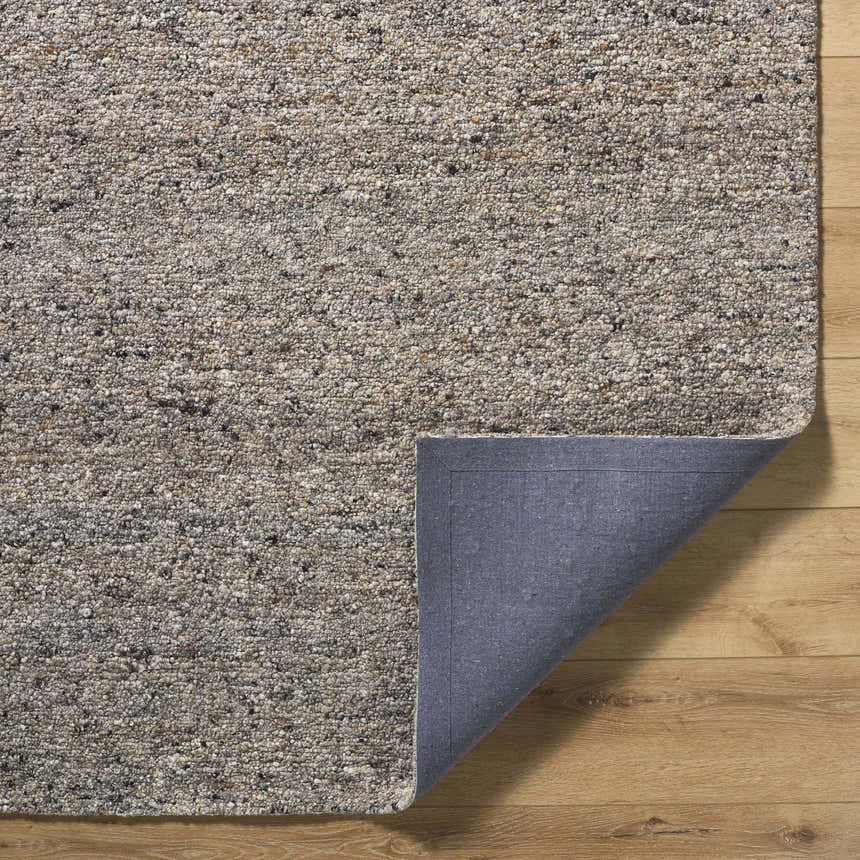 Close-up of the hand-tufted Sevan Taupe Wool Area Rug showing its neutral colors and textured wool pile on a wood floor. Fold