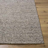 Close-up of the textured Sevan Taupe Wool Area Rug on wood floor. Neutral farmhouse style rug. Front