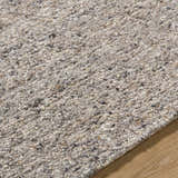 Close-up of the hand-tufted Sevan Taupe Wool Area Rug, showing texture and neutral colors with dark purple, gray, and sage accents. Texture
