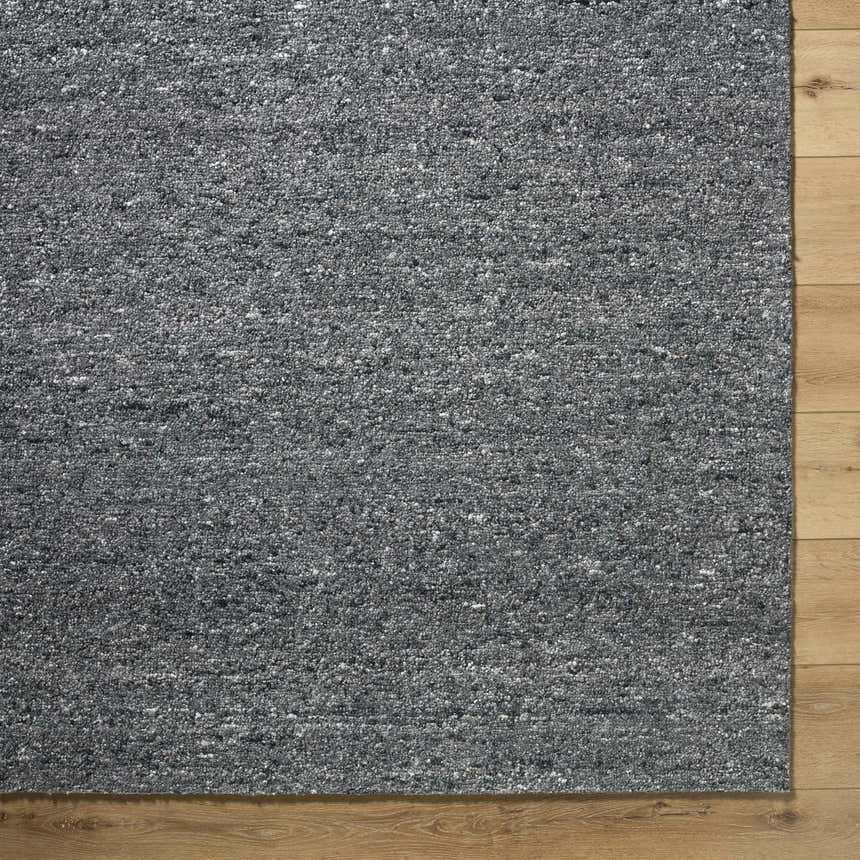 Close-up of the charcoal gray Sevan Wool Area Rug showing its textured, hand-tufted weave and neutral color palette. Corner