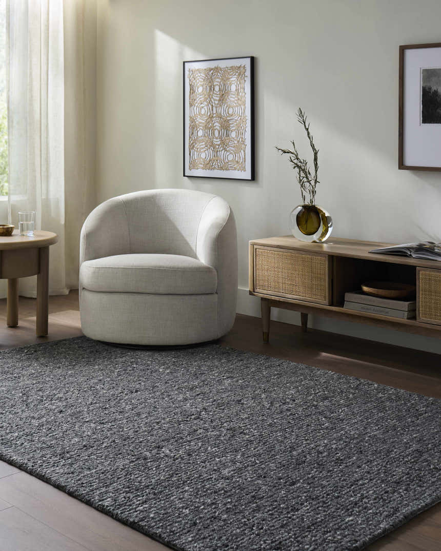 Living room scene with a gray Sevan Charcoal Wool Area Rug, cream chair, and wood media console. Roomscene-Rectangle