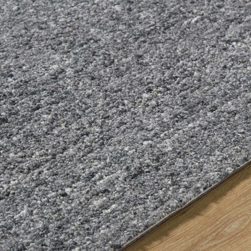 Close up of the hand-tufted Sevan Charcoal Wool Area Rug showing its gray, black, and steel gray tones and wool texture. Texture