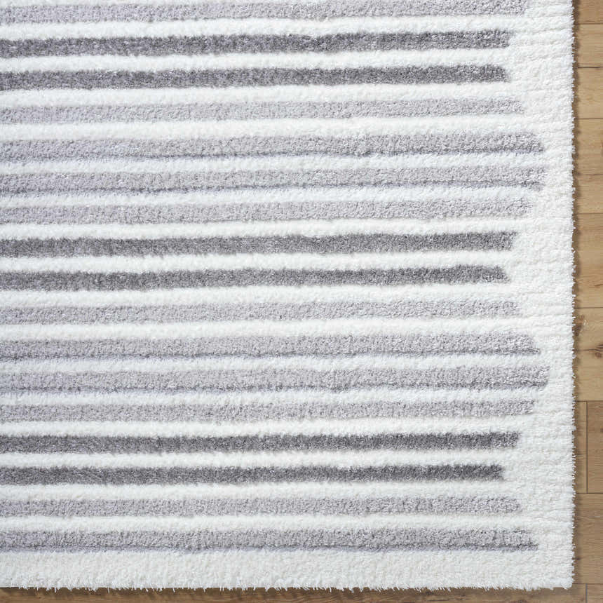 Close-up of the Buono Rose Cream Area Rug featuring a shag texture and horizontal stripes in beige and gray tones. Corner