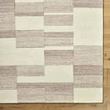 Close-up of the Eyad Area Rug, showcasing its beige and brown geometric block and striped pattern. Hand-tufted texture detail. Corner