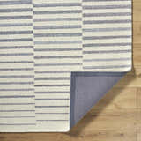 Close-up of Gawel Gray Area Rug showing a contemporary gray and ivory striped design and hand-tufted texture. Fold