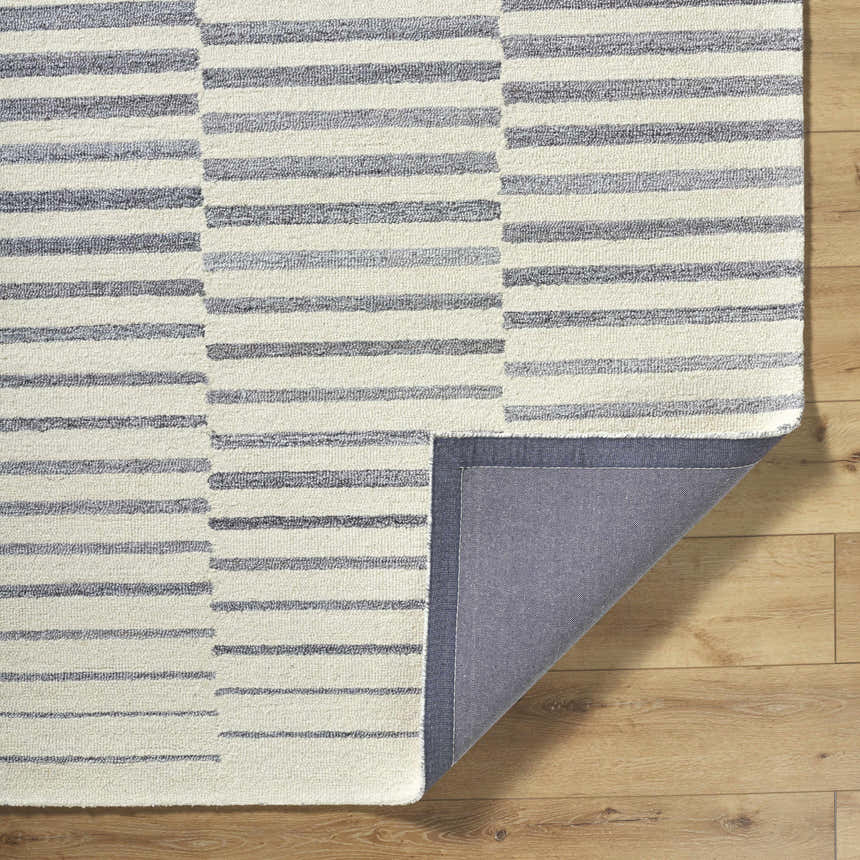 Close-up of Gawel Gray Area Rug showing a contemporary gray and ivory striped design and hand-tufted texture. Fold