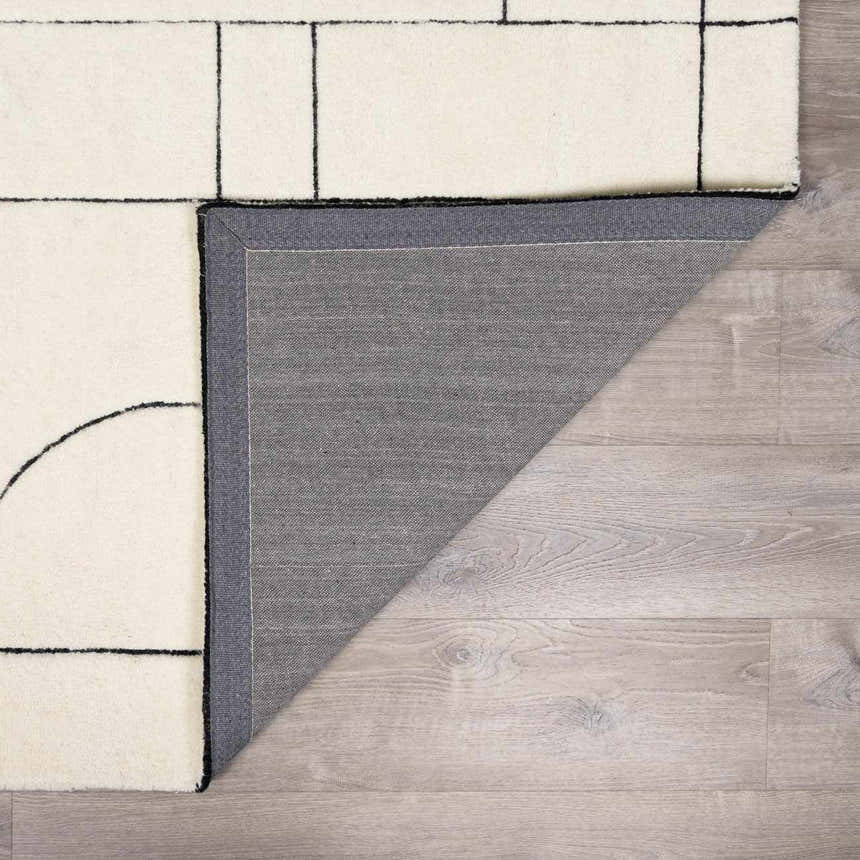 Close-up of the Fusao Rose Cream Area Rug showing its geometric design, cream color, and wool texture. Fold