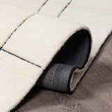 Close-up of the Fusao Rose Cream Area Rug showing the wool texture, geometric pattern, and rolled edge. Fold