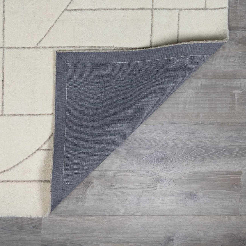 Close up of the Fusao Off White Area Rug showing the wool texture, geometric design, and rug backing. Fold