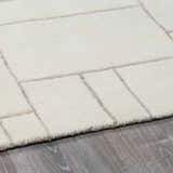 Close up of the Fusao Off White Area Rug showing its geometric pattern and wool texture. Pile