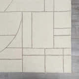 Close-up of the hand-tufted Fusao Off White Area Rug featuring a geometric light silver pattern on soft, off-white wool. Swatch