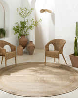 Neutral patio scene with wicker chairs and a round beige Freja Flatweave Faux Jute Rug. Earthy, contemporary style. Roomscene-Round