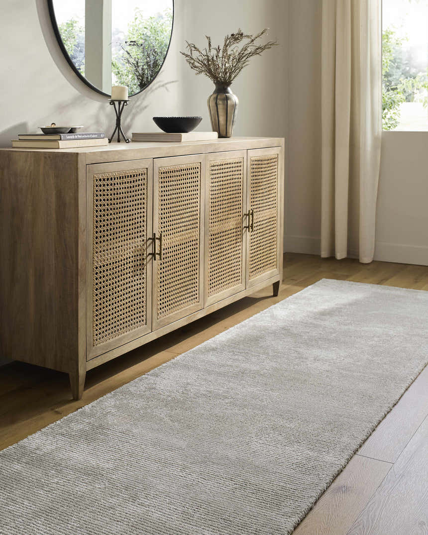 Entryway scene with a silver gray Noham Area Rug, wood floors, and a cane cabinet. Roomscene-Runner