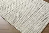 Close-up of the Salus Luxe Rug. Beige and cream rug with a contemporary black striped pattern. Corner
