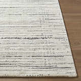 Close-up of the Salus Luxe Rug. Beige and white rug with a subtle black horizontal line pattern. Contemporary style. Front