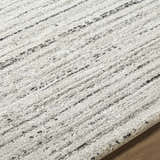 Close-up of the Salus Luxe Rug. Beige rug with a textured, contemporary design and subtle black stripes. Texture