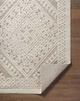 Close-up of the Hibah Bone Area Rug showing its beige geometric pattern and woven texture on a wood floor. Fold