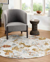 Living room scene with gray chair on a round Ouida Floral Rug in copper, silver, and natural tones. Roomscene-Round