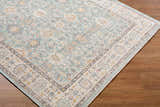 Close-up of the Adilet Blue Washable Area Rug, a farmhouse style rug with a traditional pattern in blue, gold, and gray. Corner