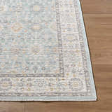 Close-up of the Adilet Blue Washable Area Rug showing its traditional pattern, light blue, gray, gold, and ivory colors. Front