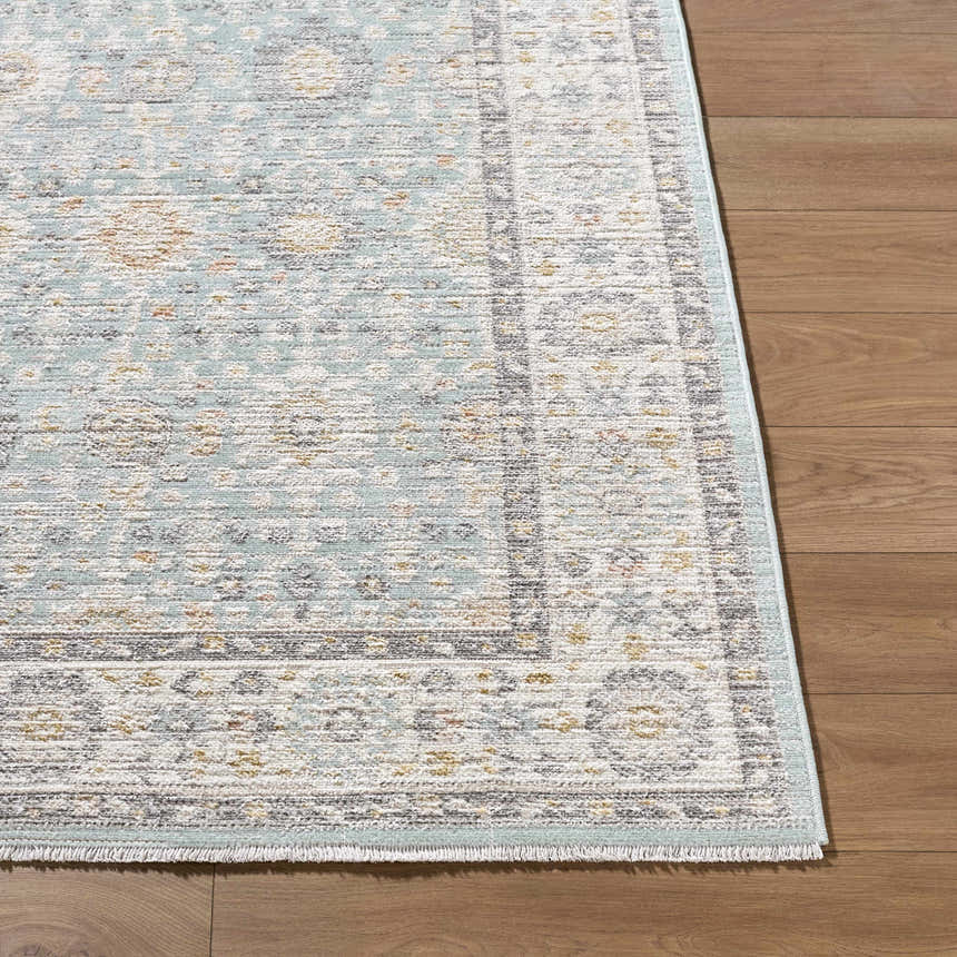 Close-up of the Adilet Blue Washable Area Rug showing its traditional pattern, light blue, gray, gold, and ivory colors. Front