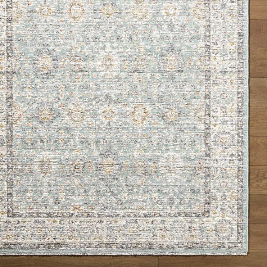 Close up of the Adilet Blue Washable Area Rug showing its traditional pattern, blue, gold, and gray colors, and woven texture. Corner