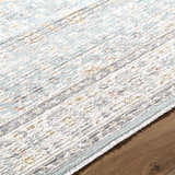 Close-up of the Adilet Blue Washable Area Rug. Farmhouse style with a traditional pattern in blue, gold, gray, and white. Texture