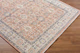 Close-up of the Adilet Dark Pink Washable Area Rug showing its traditional pattern, pink, gray, and ivory colors. Corner