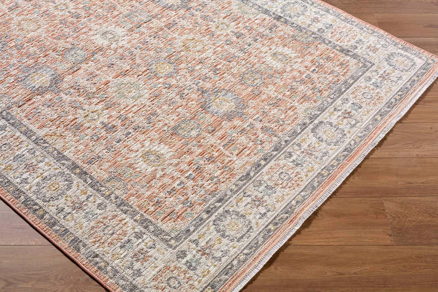 Close-up of the Adilet Dark Pink Washable Area Rug showing its traditional pattern, pink, gray, and ivory colors. Corner