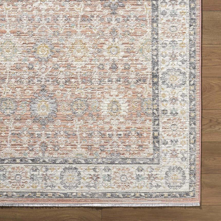 Close-up of the Adilet Dark Pink Washable Area Rug showing its traditional floral pattern, soft pink hues, and textured weave. Corner
