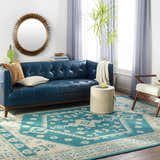 Living room scene with a teal Stepps Area Rug, blue leather sofa, round mirror, and neutral accents. Roomscene-Rectangle