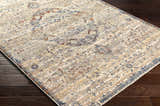 Close-up of the Stratmoor Area Rug showing its beige, blue, and burnt orange traditional design on dark wood floors. Corner