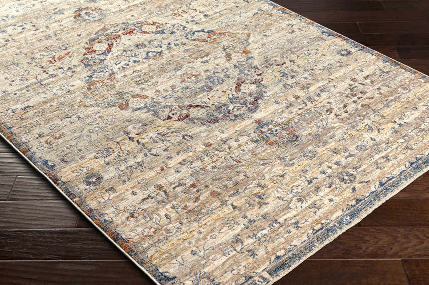 Close-up of the Stratmoor Area Rug showing its beige, blue, and burnt orange traditional design on dark wood floors. Corner