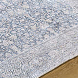 Close-up of the Lorelai Vivir x LIVABLISS washable area rug. Beige, black, and peach traditional floral pattern. Texture