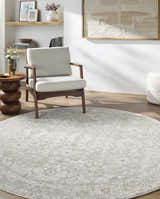 Living room scene with a round cream Tyren Area Rug, light wood floors, and neutral armchair. Roomscene-Round