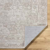 Close-up of the beige Tanko Washable Wool Area Rug showing its traditional pattern and hand-woven texture on a wood floor. Fold