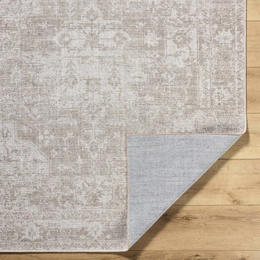 Close-up of the beige Tanko Washable Wool Area Rug showing its traditional pattern and hand-woven texture on a wood floor. Fold